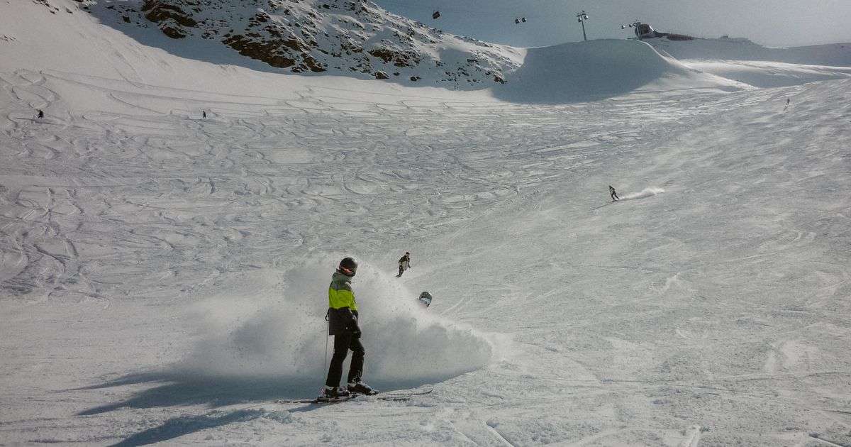 Snowboarder carving down a sunny snowy mountain slope, representing adventure sports travel insurance