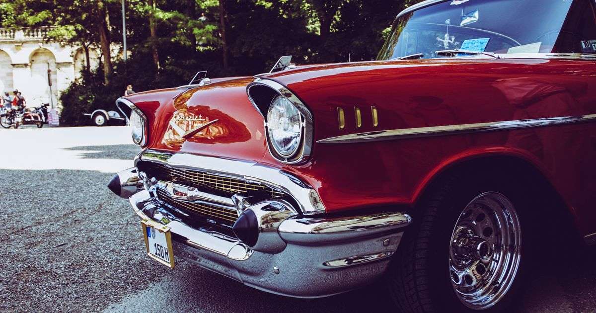 Classic red vintage car with chrome details parked outdoors in sunlight, representing classic car insurance