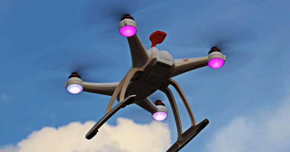 White quadcopter drone with propellers flying against a blue sky, representing drone insurance